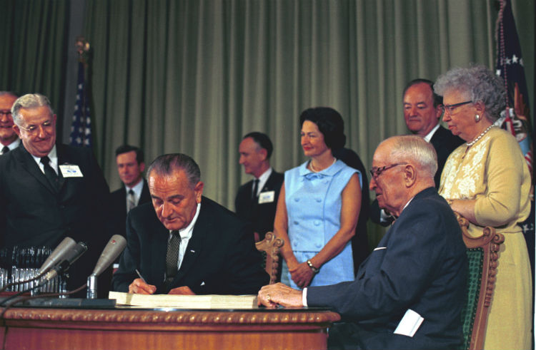 Among those with President Lyndon B. Johnson (seated) are, from left of Johnson in the foreground, Lady Bird Johnson, President Harry Truman, and Bess Truman; Vice President Hubert Humphrey is behind Truman. [Credit: White House Photo Office. Harry S. Truman Library, #34897-22.]